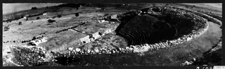 The theatre at Soli seen from above, with curved rows of stone seating cut into the slope and a surrounding stone wall.