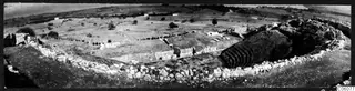 The theatre at Soli, seen from above with a curved stone wall, tiered seating and open fields beyond.