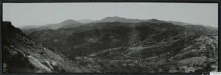 Vouni: view south over hilly country, with a winding road and a rocky outcrop in the foreground