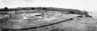 Central court at Vouni with a sunken basin, low walls and steps, with hills and the sea beyond.