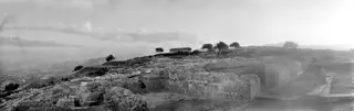View across the palace ruins at Vouni towards the summit, with stone walls, trees and hills beyond