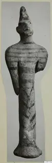 Terracotta figurine of a standing figure with a tall conical head and dark painted bands on the body