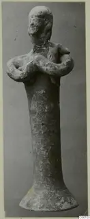 Terracotta figurine from Ayia Irini with arms folded across its chest, on a tall body with a flared base