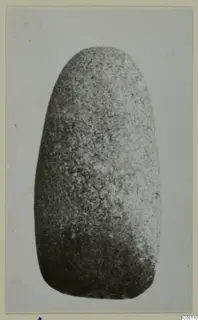 Small stone object with a rounded top and broader base, shown against a plain grey background