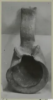Terracotta lamp with a tall handle and a broad open bowl, photographed against a plain grey backdrop