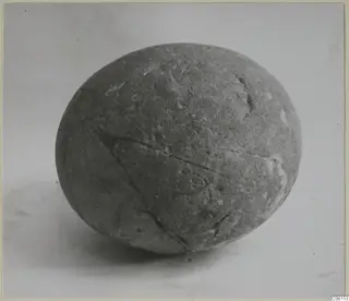 Egg-shaped grey stone, recorded as a cult stone, with cracks running across its surface