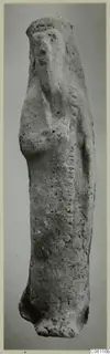 Terracotta statuette of a standing figure, upright, with a rounded head and a pitted, pale surface.