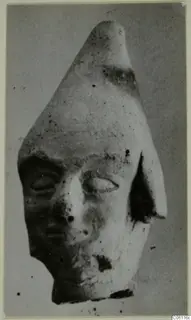 Terracotta figurine head with a tall pointed top, one ear and a broken lower edge, from Ayia Irini