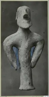 Terracotta statuette of a standing figure with arms bent at its sides, shown against a dark grey backdrop.