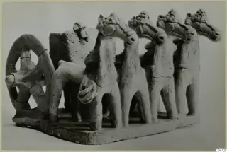 Terracotta model with a ring-shaped wheel at left and four horse-like heads in a row on a rectangular base