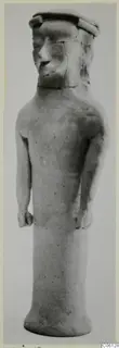 Standing terracotta figure with a cylindrical body, arms held at its sides and a flat-topped headdress from Ayia Irini