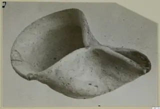 Terracotta lamp with a pinched spout, photographed from above on a light card