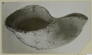 Terracotta lamp from Soli with a deep bowl and a pointed spout to the right, photographed at an angle.