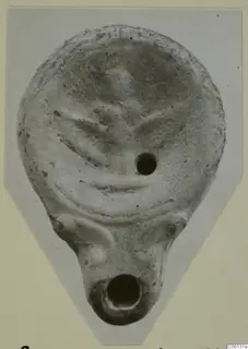 Terracotta lamp from Soli, seen from above, with raised decoration on the disc and a nozzle at the base.