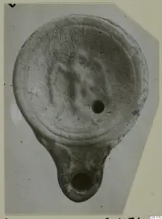 Terracotta lamp from Soli, seen from above, with a central filling hole and a projecting lug with a round opening.