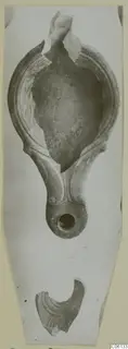 Terracotta oil lamp with a broken nozzle, shown from above, with a loose fragment below.