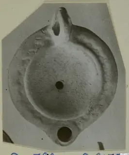 Terracotta oil lamp with a nozzle and a handle, seen from above.