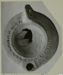 Terracotta oil lamp with a row of impressed arcs around the rim and a handle at the top