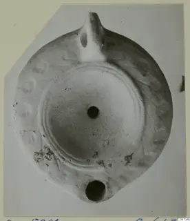 Terracotta oil lamp with a nozzle at the top and a filling hole, seen from above.