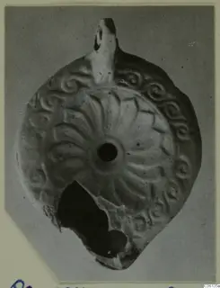 Terracotta oil lamp seen from above, with radiating leaf-like ribs and spiral motifs around the filling hole