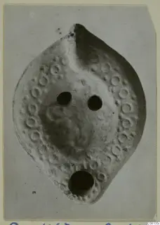 Terracotta lamp with a ring of raised circles around its rim, two filling holes and a spout hole at the base.