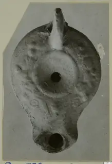Terracotta oil lamp seen from above, with a tapering nozzle at the top and a round filling hole in the centre