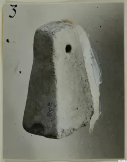 Terracotta find: a tapering block-shaped object with a round hole in one face, photographed against a grey backdrop.