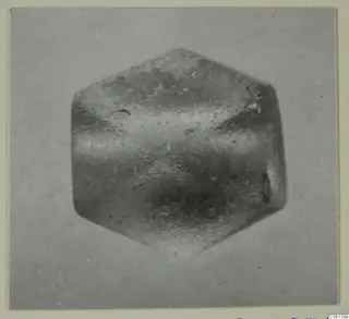Close-up photograph of a small hexagonal object with a pointed top and bottom, from the Idalion finds series