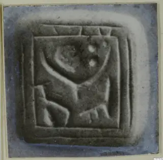 Square stone seal with a raised carved design inside a bordered frame.
