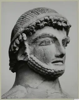 Bearded head with curled hair band, sculpted in a pale material, shown in three-quarter view