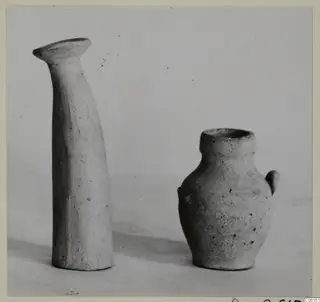 Ayia Irini pottery: a tall narrow vessel with a flared rim beside a small jug with a loop handle.