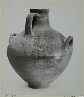 Coarse pottery jar with a narrow neck and three handles, from Idalion, photographed against a grey backdrop