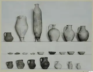 Pottery from Vouni Tomb 2 in three rows: handled jugs, two large vessels, and bowls against a plain backdrop.