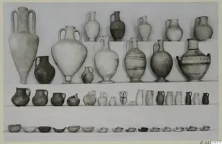 Pottery vessels from Vouni Tomb 8 arranged on three shelves: large amphorae and jugs above, small jugs in the middle, bowls below.