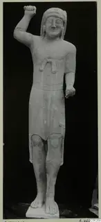 Limestone statue of a standing figure from Kition, one fist raised beside the head