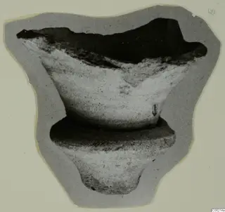 Broken pale object with a flared open top, a ring-shaped collar and a narrow foot, shown on grey card