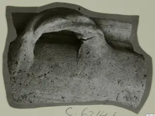 Sherd with a raised arched ridge over a dark recess, shown on a grey card mount