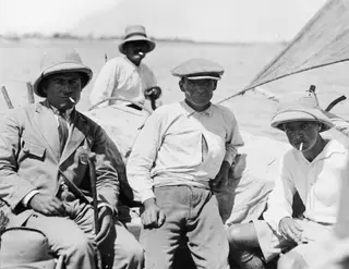 Four men seated in a small sailing boat at Baghazi, several smoking and looking towards the camera.