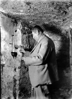 Perides lighting a small lamp inside a rock-cut chamber at Kition, Larnaca.