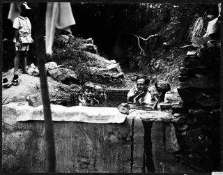 Men and boys bathing in a stone cistern at Machairas, with a boy standing on the bank watching.