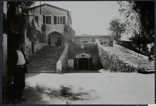 Courtyard in Nicosia with a wide stone staircase leading to an arched doorway, and a man standing at the left edge.