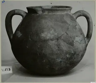 Round two-handled pottery vessel with a wide neck, cracked and repaired, shown on a plain surface.