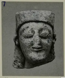 Limestone head from Kition with large eyes and a flat-topped cylindrical headdress.