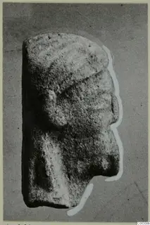 Limestone sculpture of a head in profile facing right, from Kition, photographed against a grey background