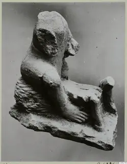 Limestone statuette of a seated figure shown in profile, one arm bent down over a rough base