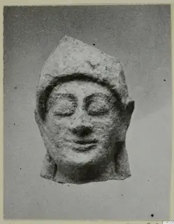 Limestone Neo-Cypriote head with downcast eyes and a cap-like headdress, shown frontally