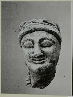 Limestone head of a statue with a wide band across the top of the head and eyes closed.