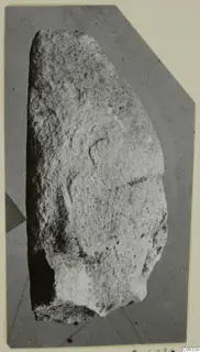Fragment of a limestone statue from Kition with shallow curved carved lines on its face and a broken lower edge.