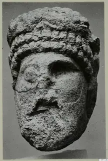Limestone head sculpture from Vouni, front view against a grey background