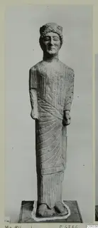 Limestone statue of a standing figure from Mersinaki, with curled hair and a draped garment with radiating folds.
